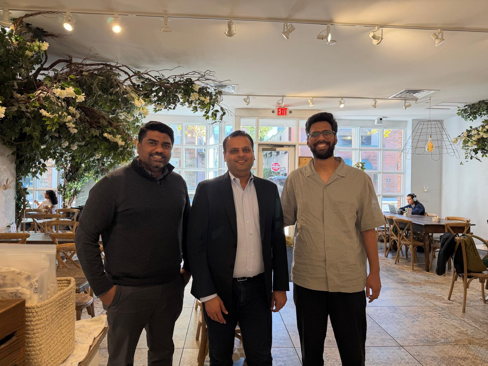 Three Next Quarter team members talking over coffee at a cafe table